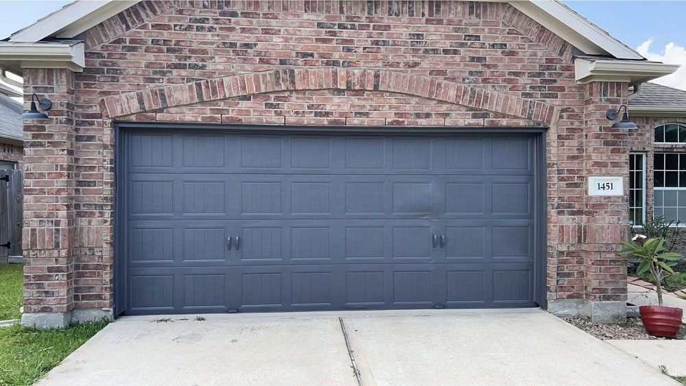 A brick house garage door repainted in dark grey