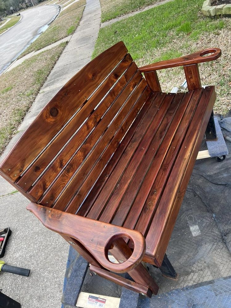 A weathered cedar bench restored to a deep red finish