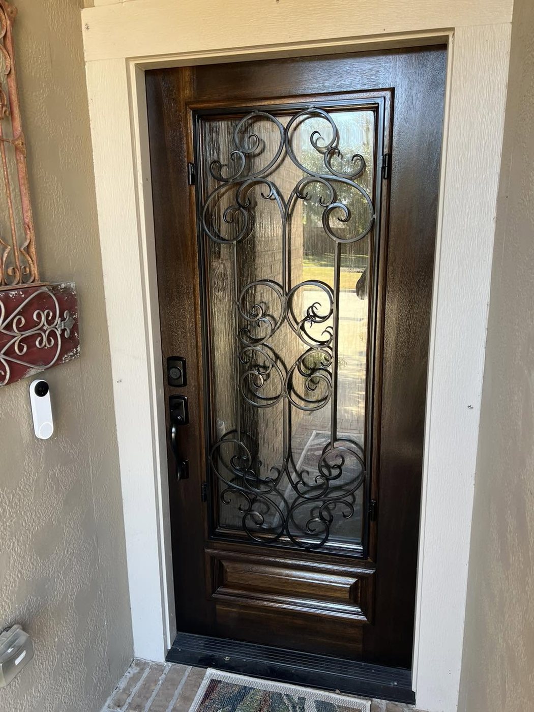 A wrought-iron scroll entry door restored to a deep walnut finish